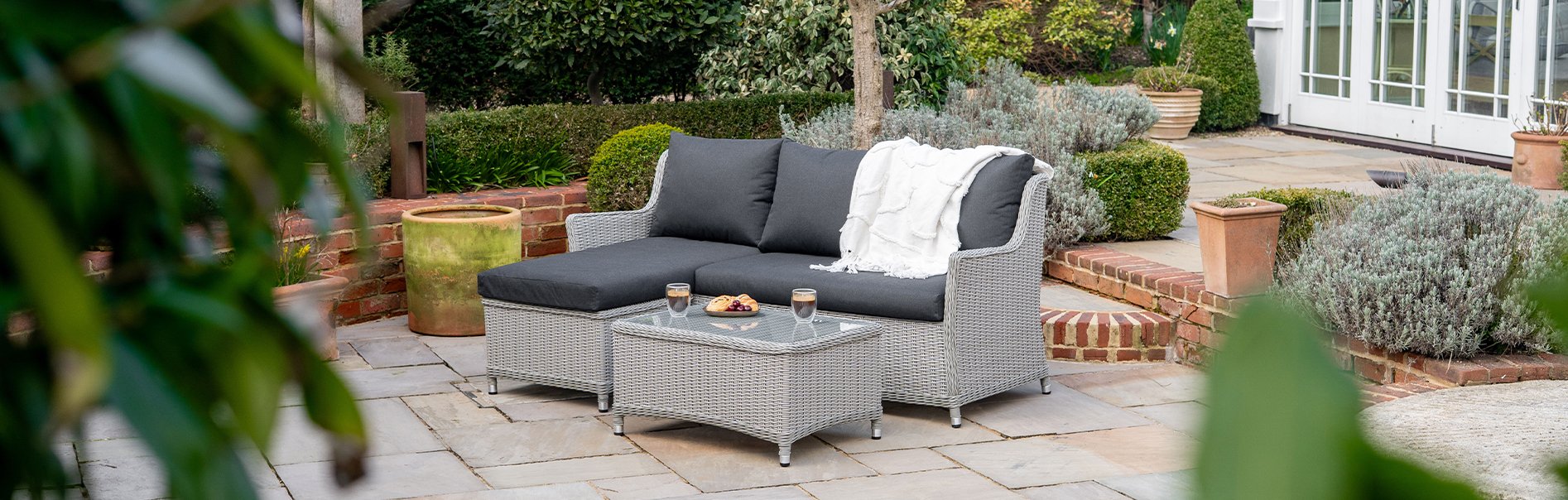 Talia light grey rattan chaise sofa in a country style garden