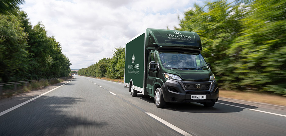 A green White Stores delivery van driving on the road