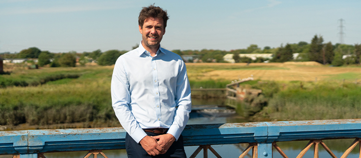 Headshot of our founder standing on a bridge, smiling