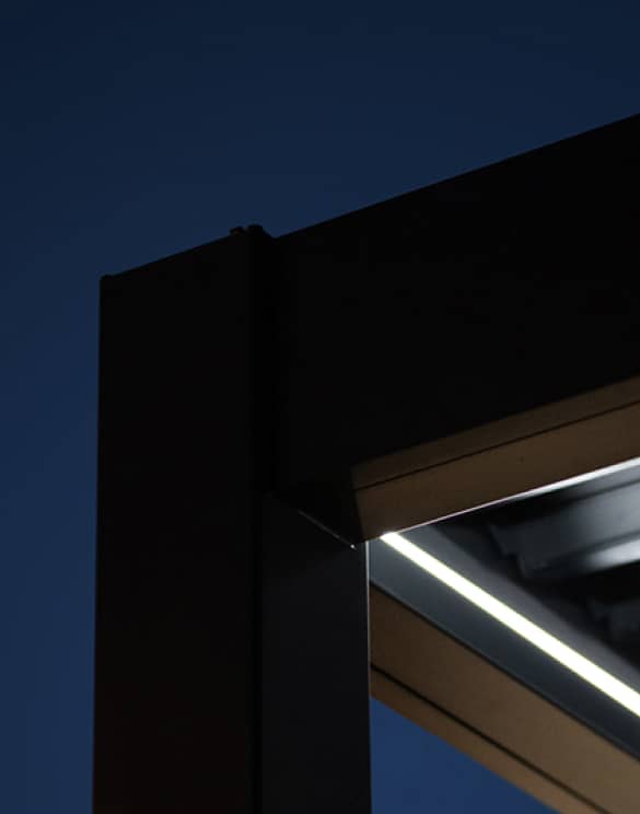 A close up of a White Stores aluminium pergola, with LED lights under the roof, at night time. 